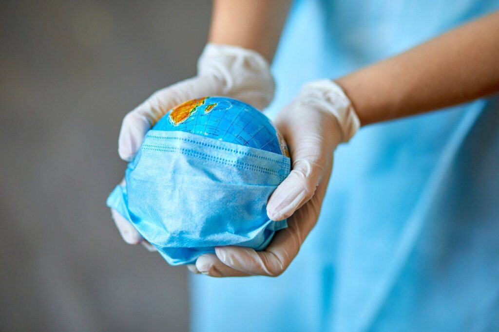 Globe in a medical mask in the hands of the doctor